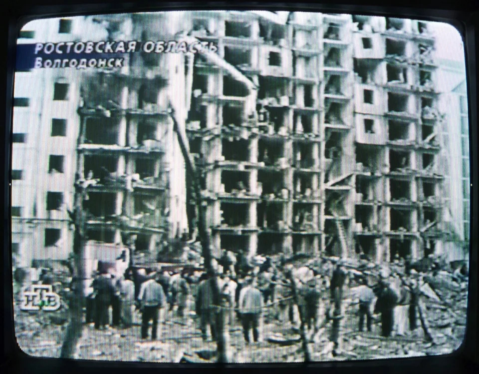A TV screen shows a destroyed apartment building.