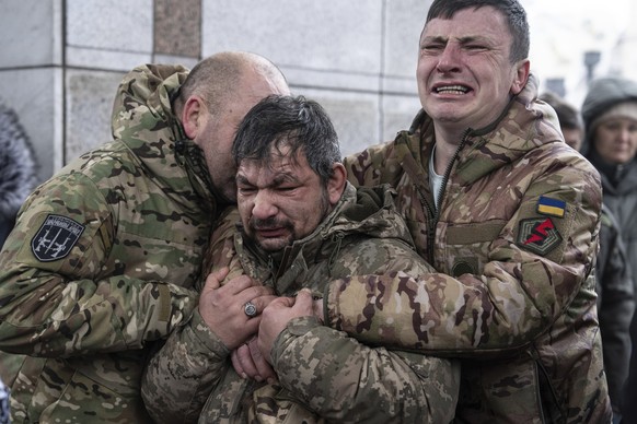 December 15, 2023, Ukraine, Kiev: Ukrainian soldiers cry next to the coffin of their comrade Andrii Trachuk during his funeral service on Independence Square.  Trachuk was a veteran of the Revolution of...