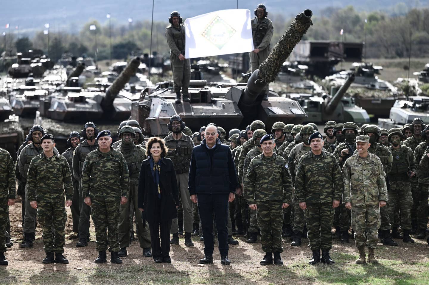 Greek Minister of Defense Nikos Dendias (center, right) and French Ambassador to Greece Laurence Auer (center, left) pose with soldiers during the Olympic Cooperation 23 exercise at the Petrochori training area, near Xanthi, northern Greece, on November 24, 2023. <em>Photo by SAKIS MITROLIDIS/AFP via Getty Images</em>