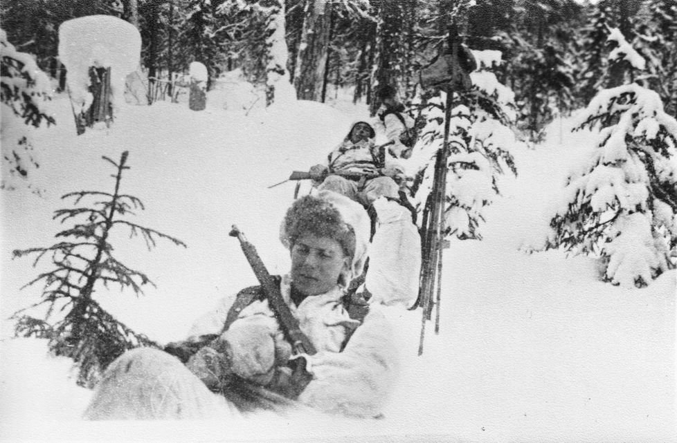 Uupuneet miehet lepäävät hangessa. Edessä Karl-Johan Norrgård.