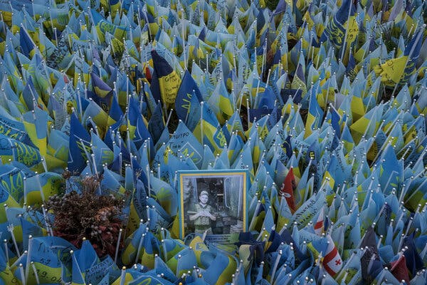 Blue-and-yellow flags surrounding a framed photograph also with the Ukrainian colors.
