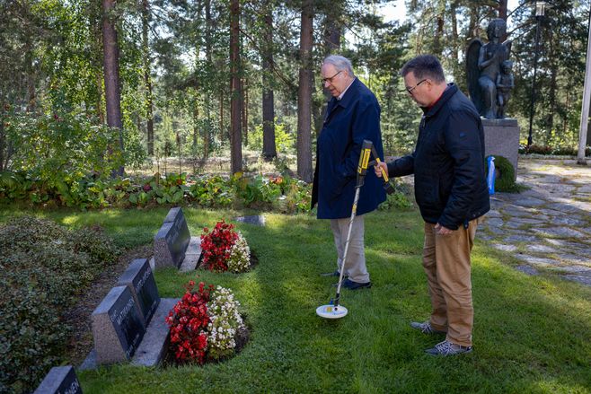 kaksi miestä hautausmaalla metallinpaljastimien kanssa.