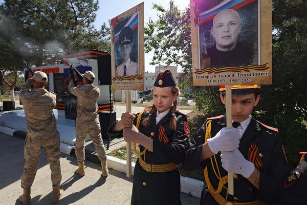 Children in military-style uniforms hold portraits of fallen soldiers as two soldiers fire their weapons into the air in the background during the opening ceremony of a memorial to the dead in Crimea in May. 