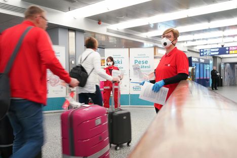 THL:n ja SPR:n työntekijät jakoivat tietoa koronakaranteenista Suomeen palaaville matkustajille Helsinki-Vantaan lentoasemalla keskiviikkona.