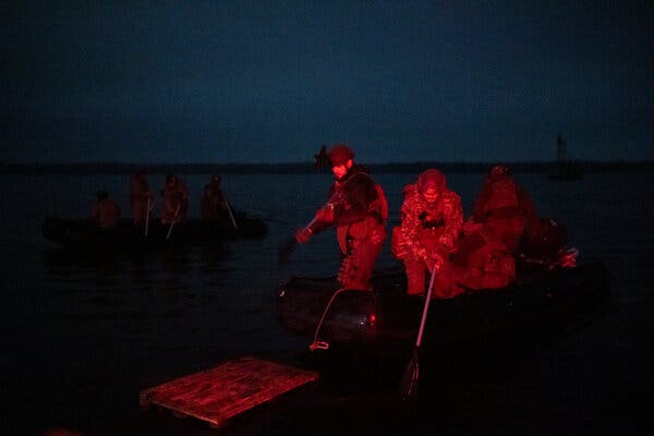 Soldiers walking at night, lit up with a reddish light.