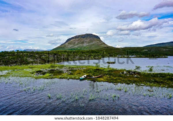 Aerial drone view of lake Tshahkajarvi, boast the Saanatunturi fell in the background, cloudy, summer day, in Kilpisjarvi, Enontekio, Lapland, Finland