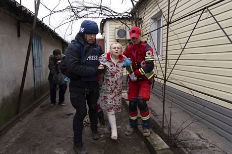 Valokuvaaja Jevgeny Maloletka auttaa ensihoitajaa viemään haavoittunutta naista turvaan.