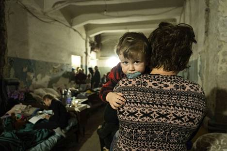 Nainen rauhoittelee lasta pommisuojassa Mariupolissa.