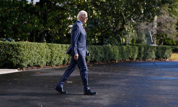 President Biden walking outside in a blue suit.