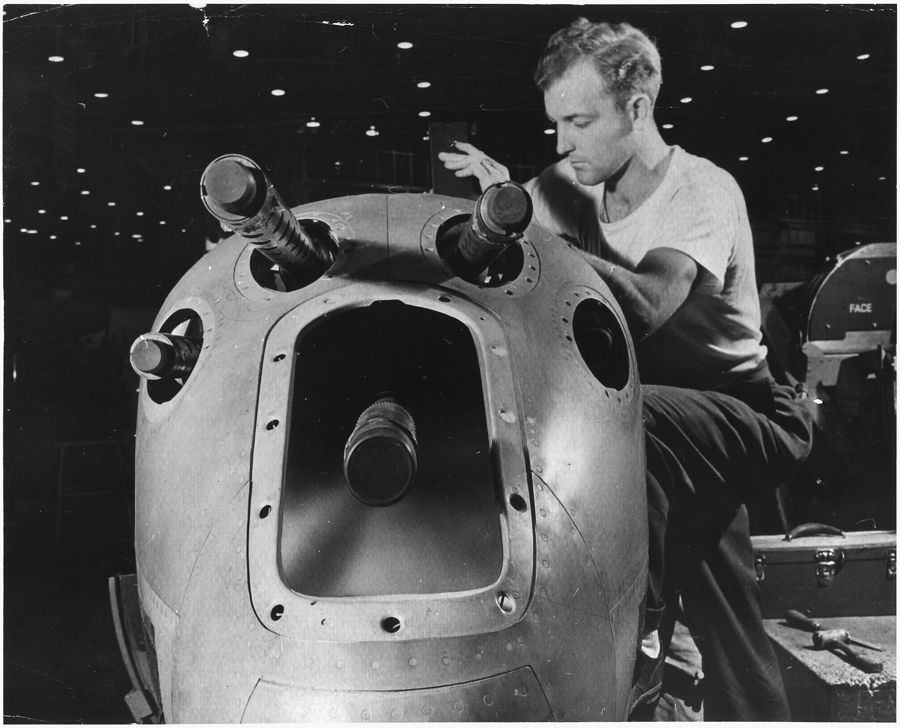 An_armorer%27s_assistant_in_a_large_western_aircraft_plant_works_on_the_installation_of_one_of_the_machine_guns_in_the..._-_NARA_-_196367.jpg