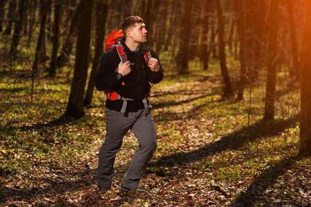 56661854-hiker-wearing-hiking-backpack-and-hardshell-jacket-on-hike-in-forest-man-wearing-hat-gloves-using-hi.jpg