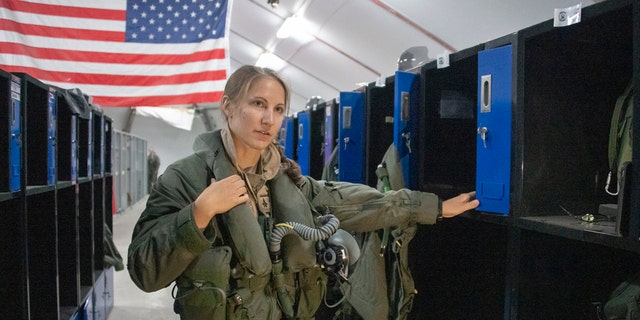 U.S. Air Force Capt. Emily Thompson, 421st Expeditionary Fighter Squadron pilot, dons flight equipment at the Aircrew Flight Equipment shop on Al Dhafra Air Base, United Arab Emirates, June 5, 2020. Thompson is the first female to fly an F-35A Lightning II into combat. She is currently deployed from Hill Air Force Base, Utah. 