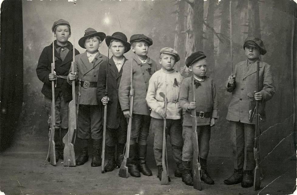 ”Pikkupunakaartilaiset” valokuvattiin Kymissä sisällissodan aikaan vuonna 1918. Seitsemästä pojasta kuudella on leikkiase, yhdellä oikea.