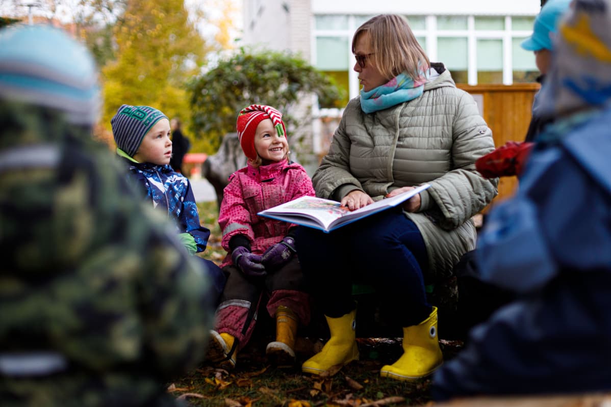 Lastentarhanopettaja Birgitta Tints lukee satua Tammetõrun päiväkodin lapsille. Johannes ja Karin kuuntelevat.