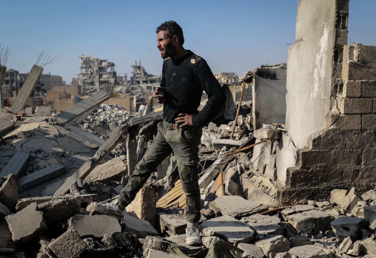Mies seisoo tuhoutuneen kotitalonsa katolla Syyrian Raqqassa.