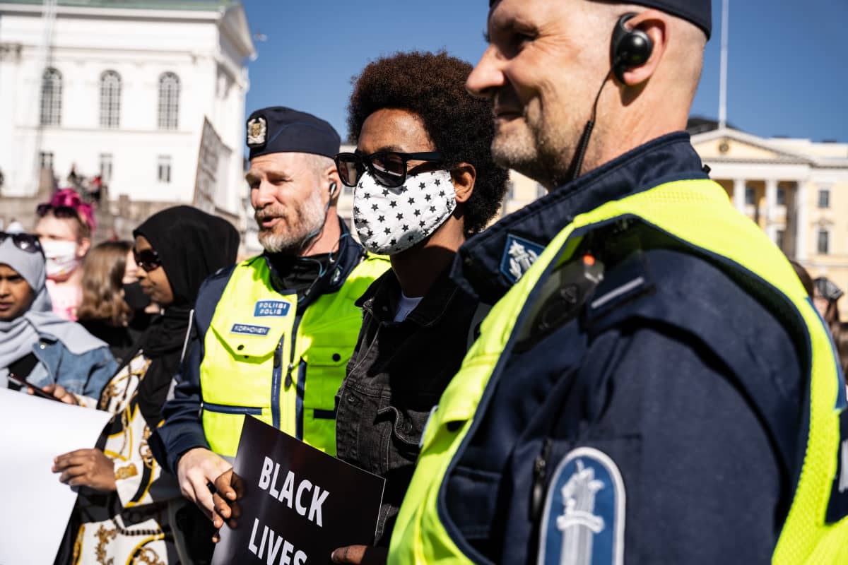 En demonstrant står mellan två poliser. En demonstrant står mellan två poliser.