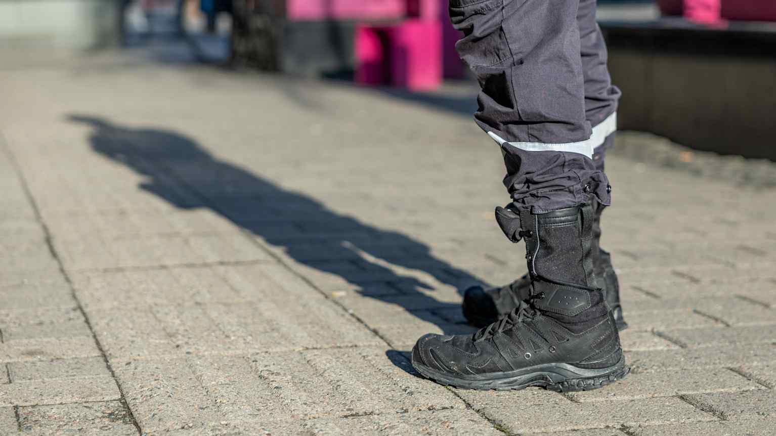 Järjestyksenvalvojan kengät ja jalat joista piirtyy maahan ihmisen silhuetti. Järjestyksenvalvojan kengät ja jalat joista piirtyy maahan ihmisen silhuetti.
