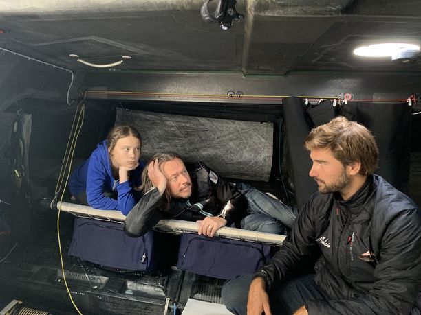 Greta Thunberg, hänen isänsä Svante Thunberg ja laivan kapteeni Boris Herrmann sisällä Malizia II -kilpapurjeveneessä, jolla noin kaksi viikkoa kestävä Atlantin ylitys tehdään.