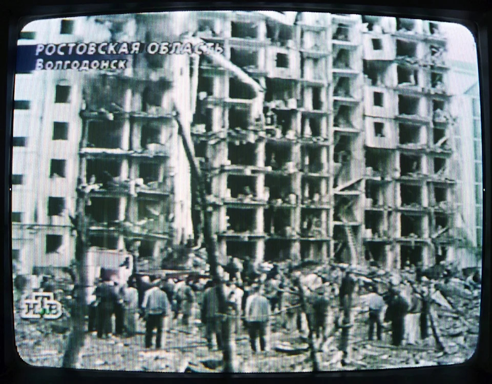 A TV screen shows a destroyed apartment building. A TV screen shows a destroyed apartment building.